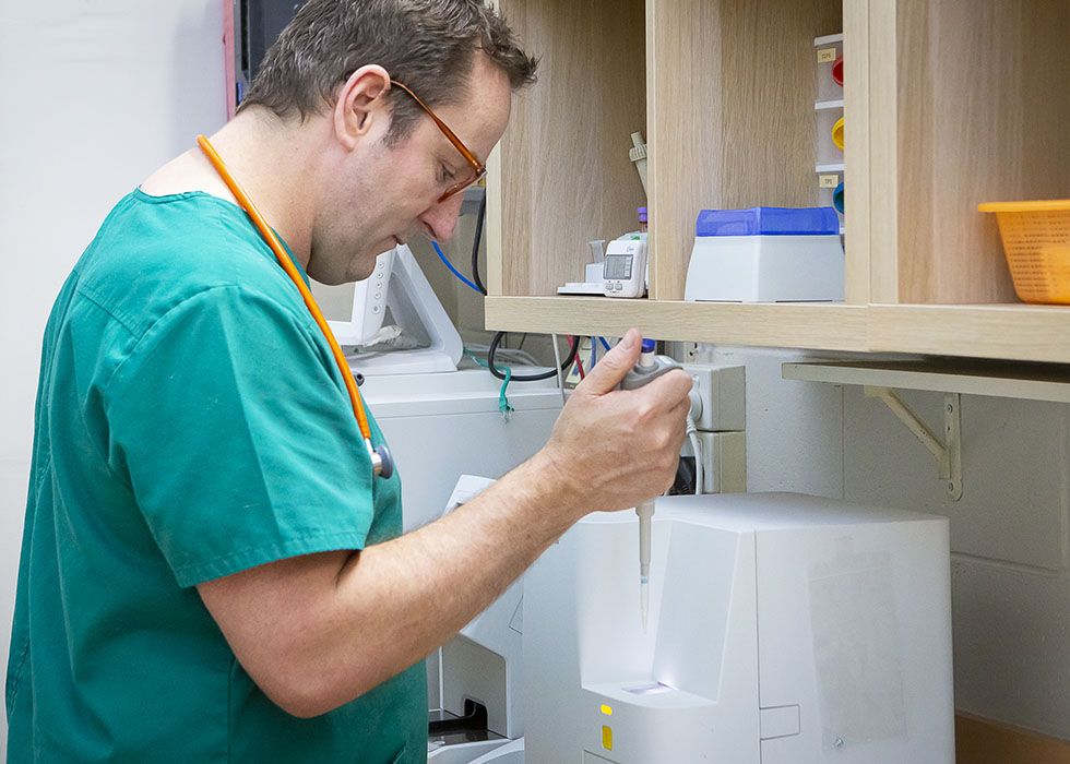 A male healthcare professional in scrubs operating medical equipment.